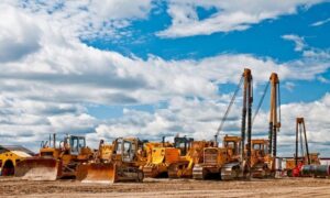 Alat berat konstruksi seperti excavator dan bulldozer sedang dioperasikan oleh tenaga profesional di lokasi proyek
