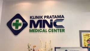 Logo Klinik Pratama MNC Medical Center dengan simbol palang hijau di dinding putih